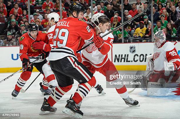 Bryan Bickell of the Chicago Blackhawks and Cory Emmerton of the Detroit Red Wings watch for the puck during the NHL game on March 16, 2014 at the...