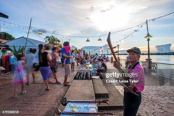 Musician busks for change at a night market set up long the Mekong River in the Issarn town of Nong Khai.