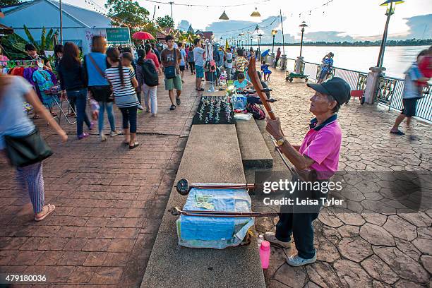 Musician busks for change at a night market set up long the Mekong River in the Issarn town of Nong Khai.