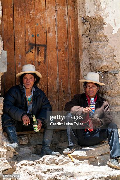 Khampa nomad men rest in the shade of a rammed earth house in a village in Sichuan.