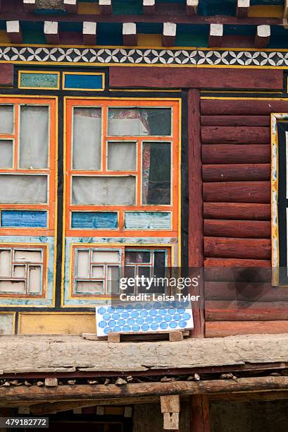 Window of a traditional wooden house with solar panel fueling a light bulb in Axu county, Western Sichuan.
