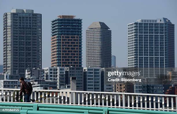 Pedestrian cycles along a footbridge past residential and commercial buildings in the Toyosu area of Tokyo, Japan, on Sunday, March 16, 2014. Japan's...