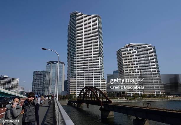 Pedestrians walk along a footbridge past residential and commercial buildings in the Toyosu area of Tokyo, Japan, on Sunday, March 16, 2014. Japan's...