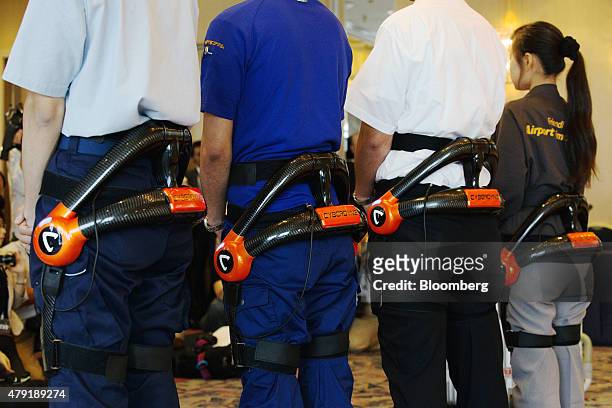 Japan Airport Terminal Inc. Employees pose for a photograph while wearing the Hybrid Assistive Limb exoskeleton robot suit developed by Cyberdyne...