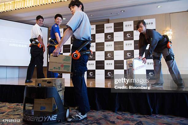 Japan Airport Terminal Inc. Employees poses for a photograph while wearing the Hybrid Assistive Limb exoskeleton robot suit developed by Cyberdyne...