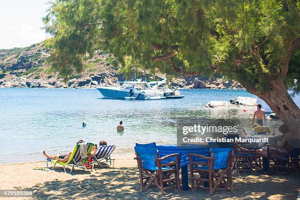 Tourist relax under a tree on the beach during midday next to the town of Faros on June 19, 2015 in Sifnos, Greece. Sifnos is a island in the western...