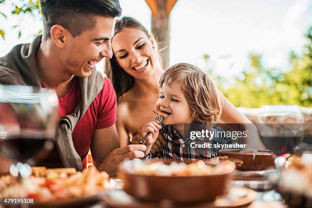 gai jeune père nourrir son fils dans le restaurant. - happy family eating photos et images de collection