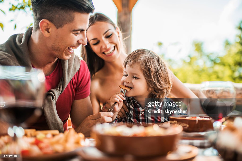 Cheerful young father feeding his son in restaurant.
