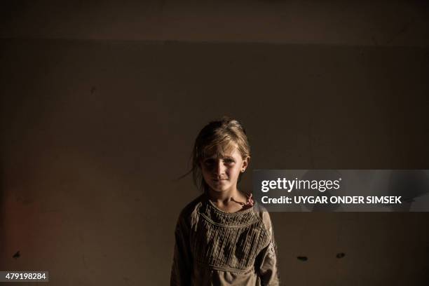 Syrian refugee girl stands in a building on June 27, 2015 in Syrian Kurdish city of Amuda, after running away from clashes between regime forces and...