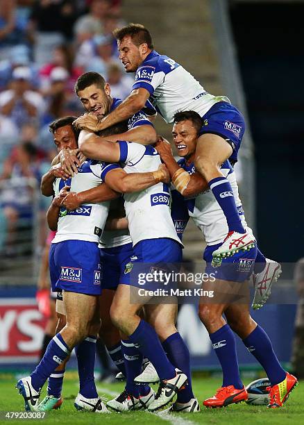 Bulldogs players celebrate the try to Michael Ennis as Josh Reynolds jumps over the top during the round two NRL match between the...