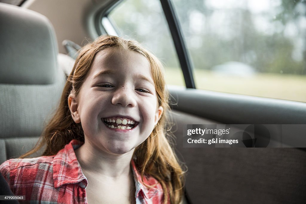 Girl (7) laughing in backseat of car