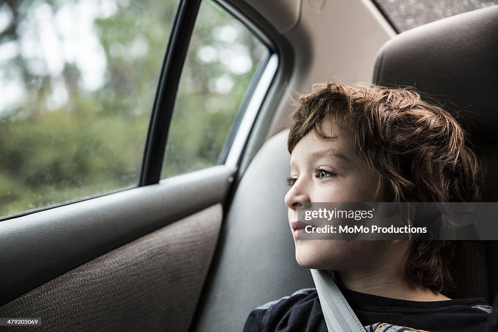 Boy (9 in backseat of car, looking out window