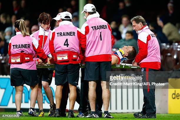 Ted Richards of the Swans is put in a neck brace and is assisted from the field by medical staff after sustaining an injury during the round 14 AFL...