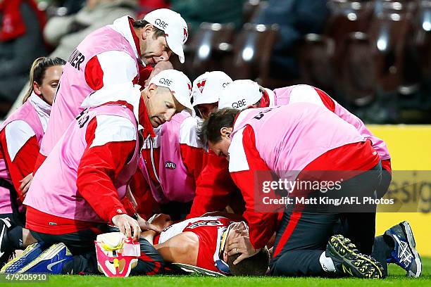 Ted Richards of the Swans is put in a neck brace and is assisted from the field by medical staff after sustaining an injury during the round 14 AFL...