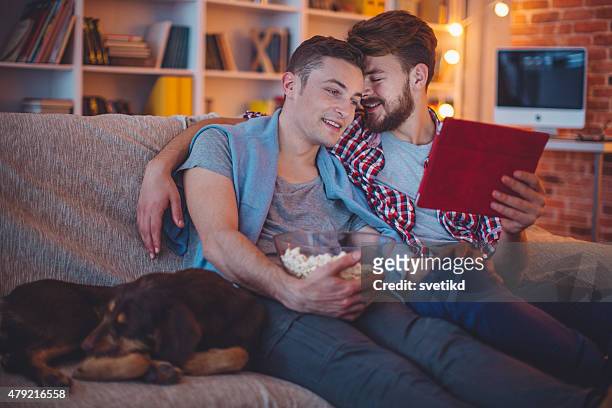 young gay couple. - watching tv couple night stock pictures, royalty-free photos & images