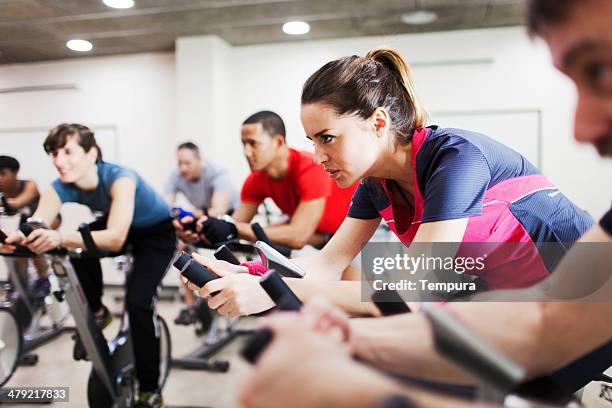 groupe de personnes pratiquant un sport dans une salle de sport. - cours de spinning photos et images de collection