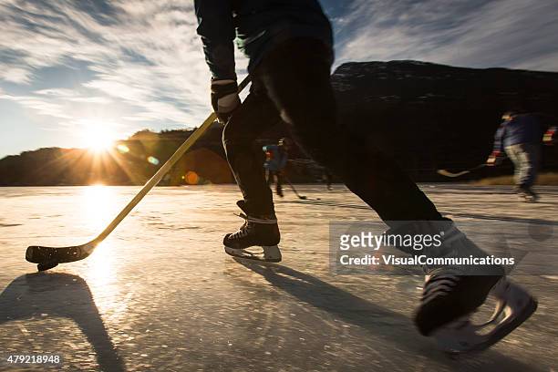 spielen eishockey auf zugefrorenen see im sonnenuntergang. - hockey player stock-fotos und bilder