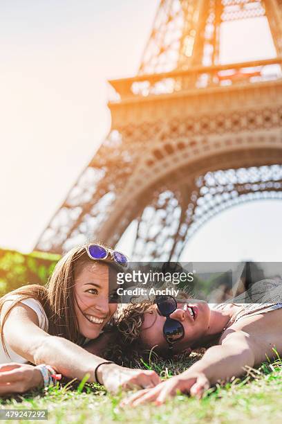 freunde lächelnd und sitzt vor eiffelturm - paris millenials stock-fotos und bilder