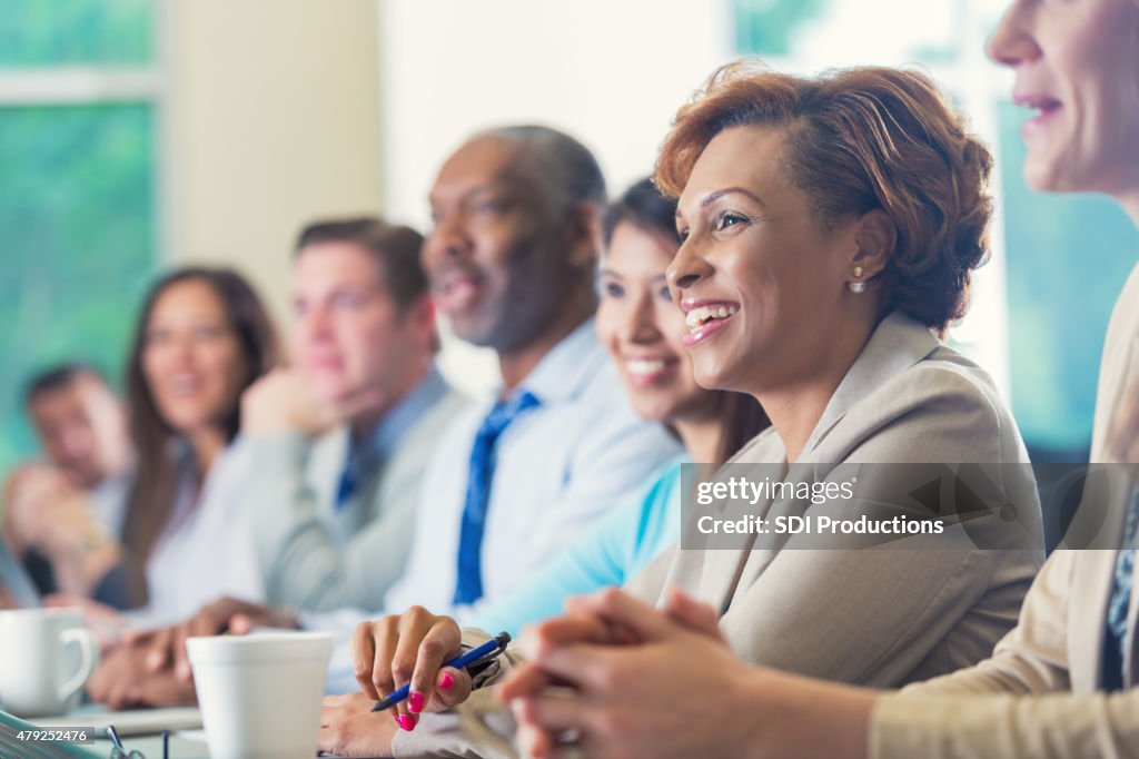 African American businesswoman listening to seminar speaker at business conference