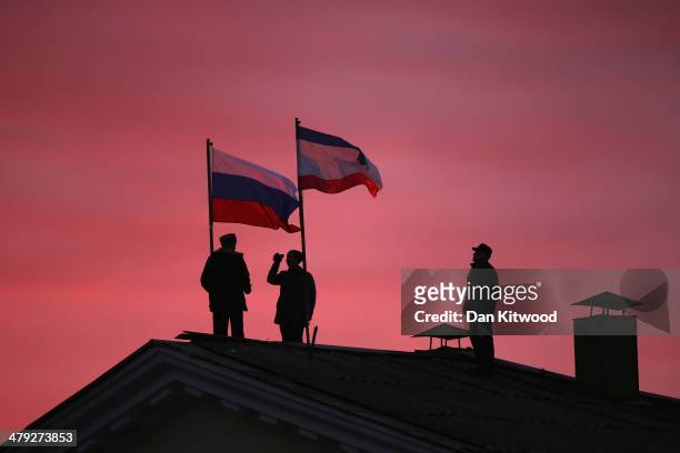 Cossack men install a Russian flag and a Crimean flag on the roof of the City Hall building on March 17, 2014 in Bakhchysarai, Ukraine. People in...