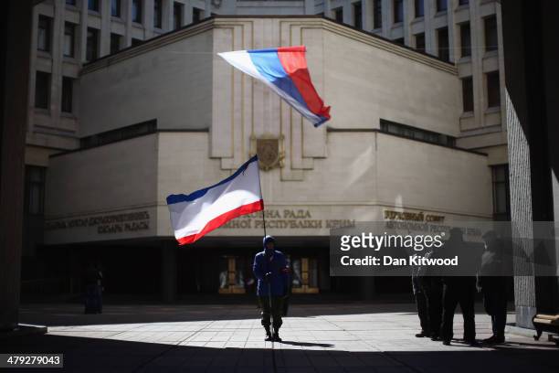 Man holds a Crimean flag in front of the Crimean parliament building on March 17, 2014 in Simferopol, Ukraine. People in Crimea overwhelmingly voted...