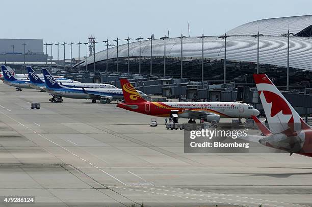 All Nippon Airways Corp. , left, and Hong Kong Airlines Ltd. Aircrafts sit parked at the Kansai International Airport, in Izumisano City, Osaka,...