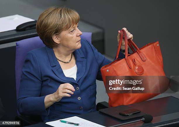 German Chancellor Angela Merkel holds her handbag while she attends a session of the Bundestag on July 3, 2015 in Berlin, Germany. The Bundestag...