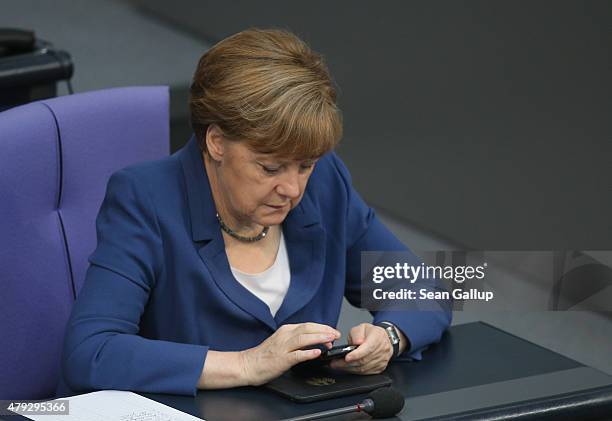 German Chancellor Angela Merkel uses a smartphone while she attends a session of the Bundestag on July 3, 2015 in Berlin, Germany. The Bundestag...