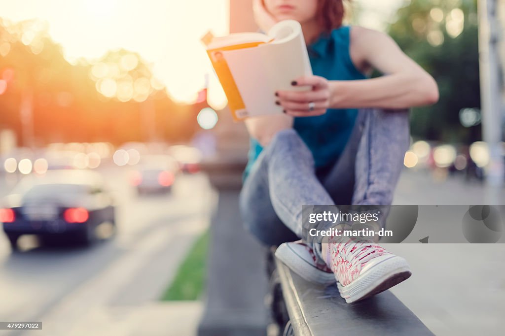 Girl reading a book in the city