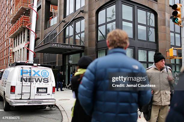 Media crews conduct interviews outside the Chelsea apartment building where fashion designer L'Wren Scott was found dead from an apparent suicide on...