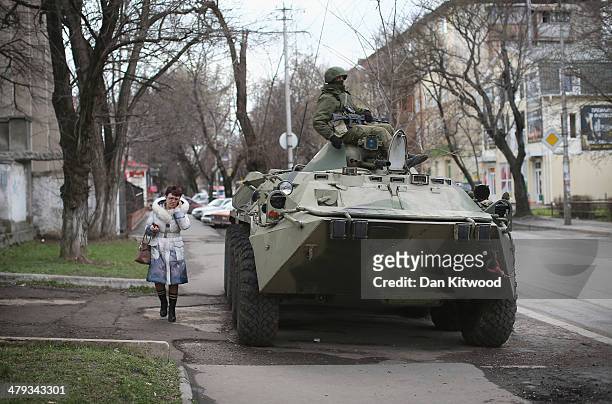 Woman walks past a Russian military personnel carrier outside a Ukrainian military base on March 18, 2014 in Simferopol, Ukraine. Voters on the...