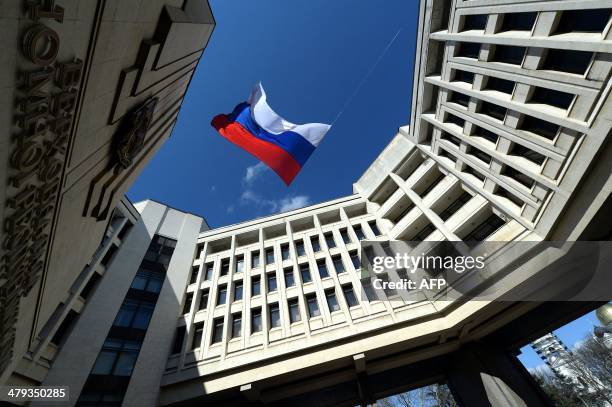 Russian flag flies in the courtyard of the parliament building in Simferopol, Crimea, on March 18 while workers dismantled the inscription reading...