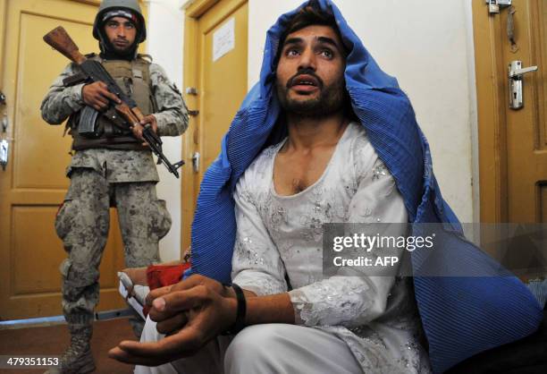 Afghan security personnel present a burqa-clad resident they say is a Taliban fighter to the media at the Afghan National Army headquarters in...