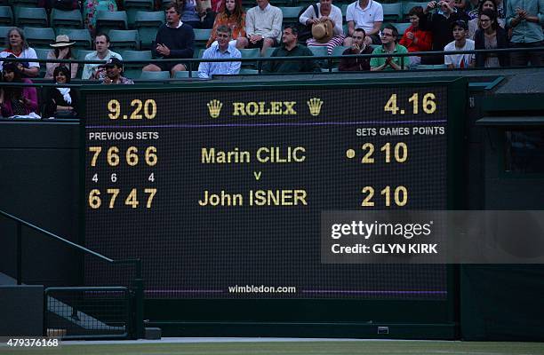 Spectators sit above the score board after the men's singles third round match between Croatia's Marin Cilic and US player John Isner was postponed...