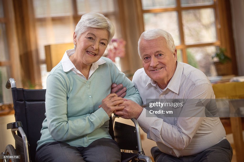 Happy senior couple at home looking at camera
