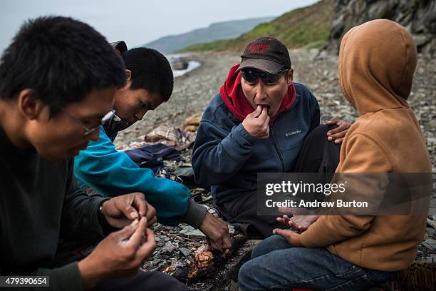 Joseph John Jr. Eats a freshly caught salmon with his sons and friends while waiting for the tide to come in after a day of salmon fishing on July 1,...