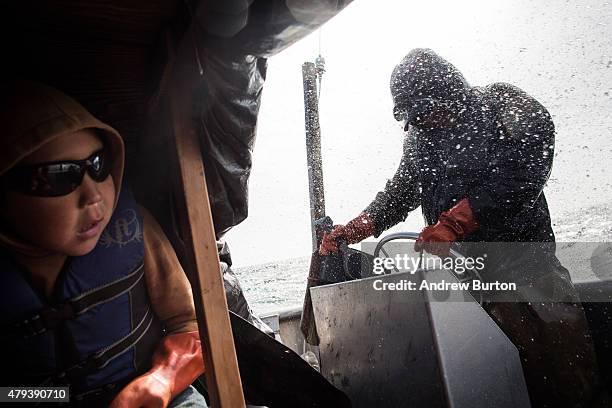 Samuel John watches as his father, Joseph John Jr., gets soaked driving the boat while salmon fishing on July 1, 2015 in Newtok, Alaska. Newtok has a...