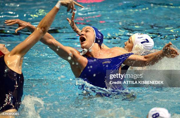 Italy's Roberta Bianconi fights with Hungary's Diana Sikter and goalkeeper Orsolya Kaso in the local swimming pool of Budapest on March 18, 2014...