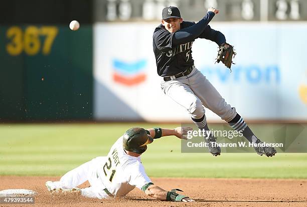 Brad Miller of the Seattle Mariners throws over the top of Stephen Vogt of the Oakland Athletics but not in time to complete the double-play in the...