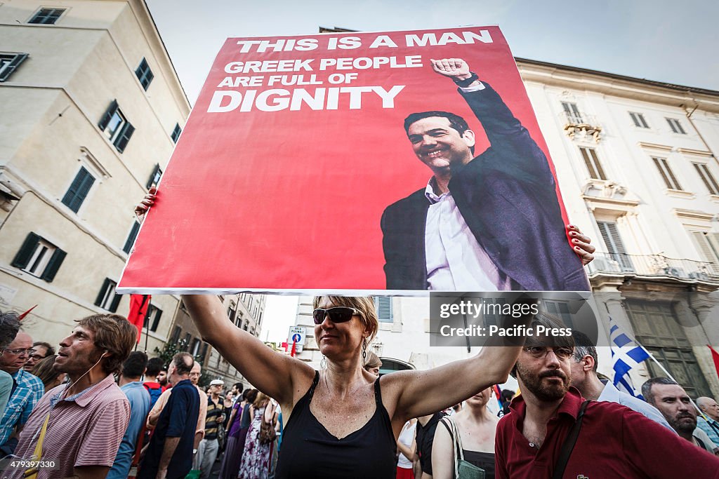 A demonstrators holds a banner with the Tsipras photo as she...