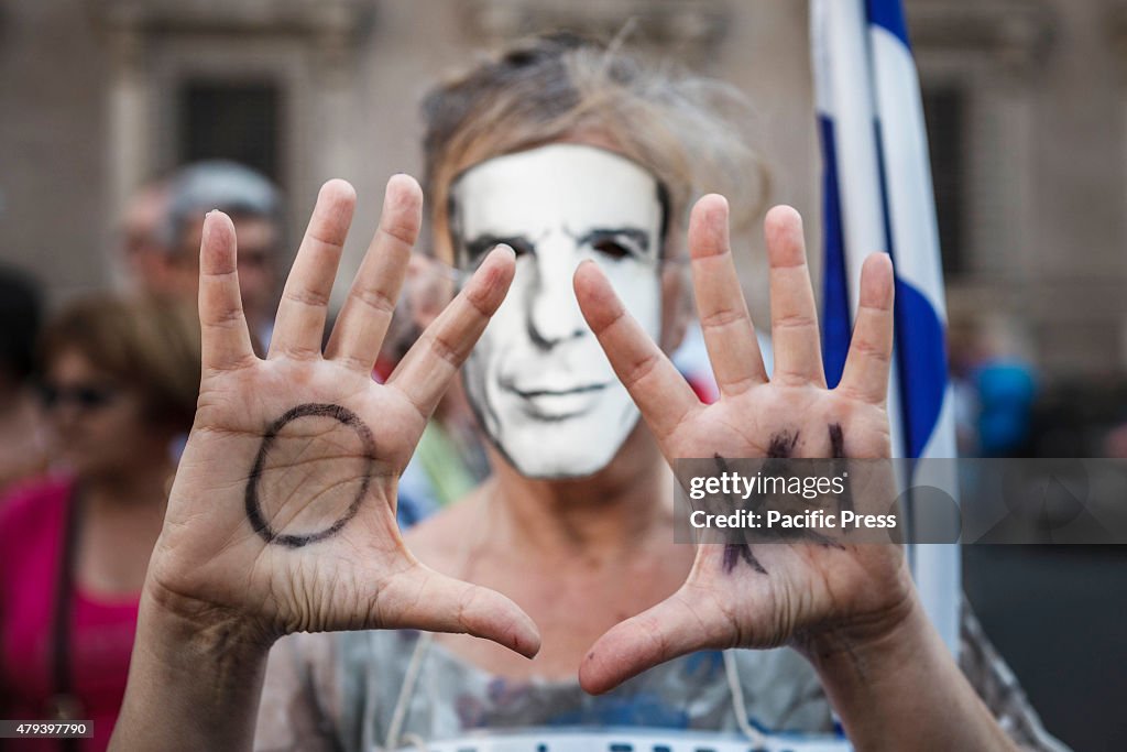 A protester shows the word 'Oki' (No in Greek) on her hands...