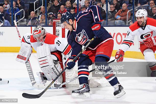 Goaltender Anton Khudobin of the Carolina Hurricanes defends as Corey Tropp of the Columbus Blue Jackets skates the puck around the net during the...