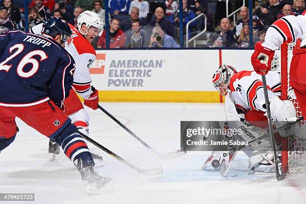 Riley Nash of the Carolina Hurricanes and Corey Tropp of the Columbus Blue Jackets watch as goaltender Anton Khudobin of the Carolina Hurricanes...