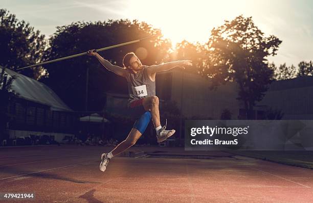 atleta lanzar un jabalina en un estadio al atardecer. - jabalina fotografías e imágenes de stock