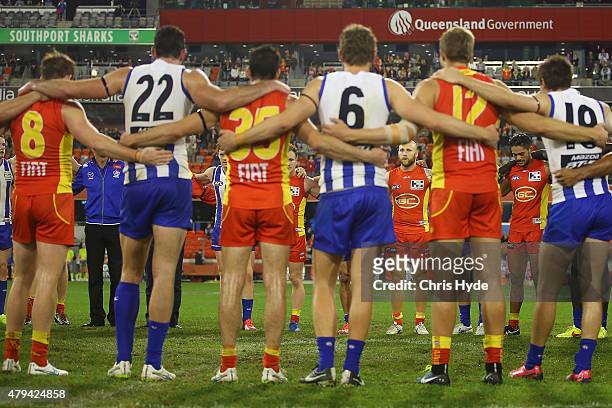 Both sides huddle in the middle of the ground to pay respect to Phil Walsh during the round 14 AFL match between the Gold Coast Suns and the North...