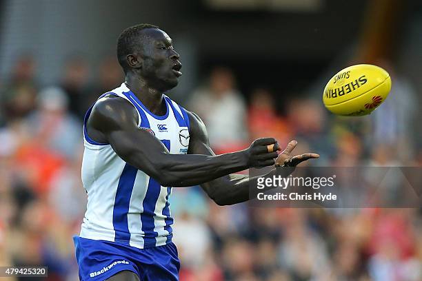 Majak Daw of the Kangaroos handballs during the round 14 AFL match between the Gold Coast Suns and the North Melbourne Kangaroos at Metricon Stadium...