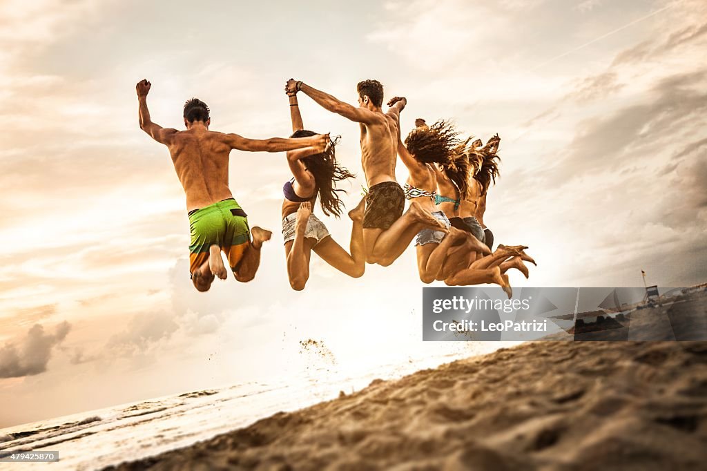 Group of friends jumping on the beach all together