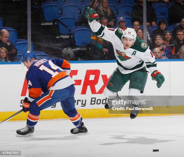 Thomas Hickey of the New York Islanders sends Zach Parise of the Minnesota Wild into the air during the first period in an NHL hockey game at Nassau...