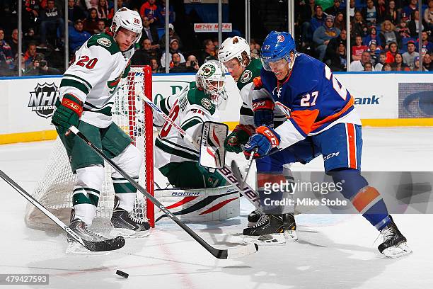Anders Lee of the New York Islanders battles for the puck with Ryan Suter of the Minnesota Wild at Nassau Veterans Memorial Coliseum on March 18,...
