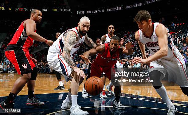 Kyle Lowry of the Toronto Raptors battles for a rebound against Pero Antic and Kyle Korver of the Atlanta Hawks at Philips Arena on March 18, 2014 in...